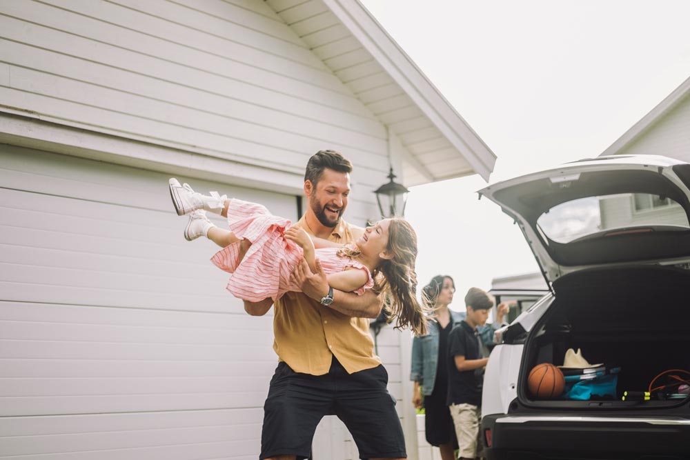 Pappa och dotter framför garage med bil